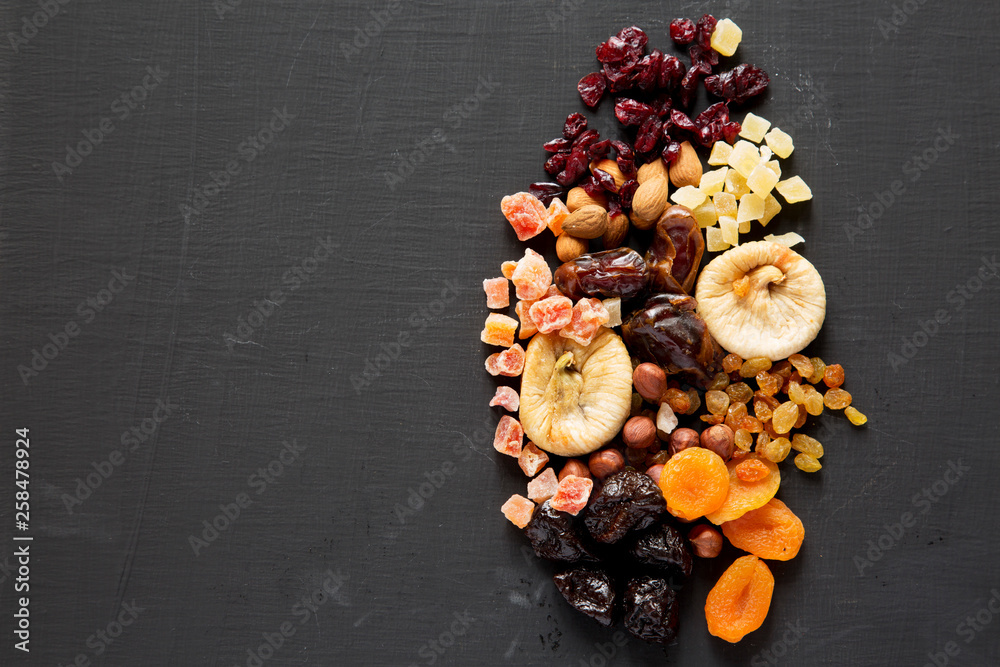Dried fruits and nut mix on black background, top view. Overhead. Copy space.