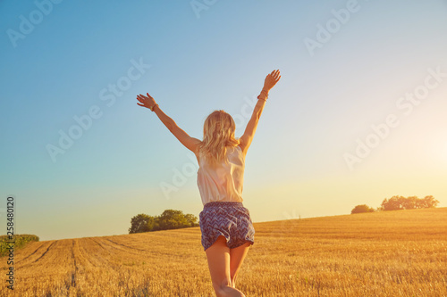 Young woman jumping and running in a wheat field.