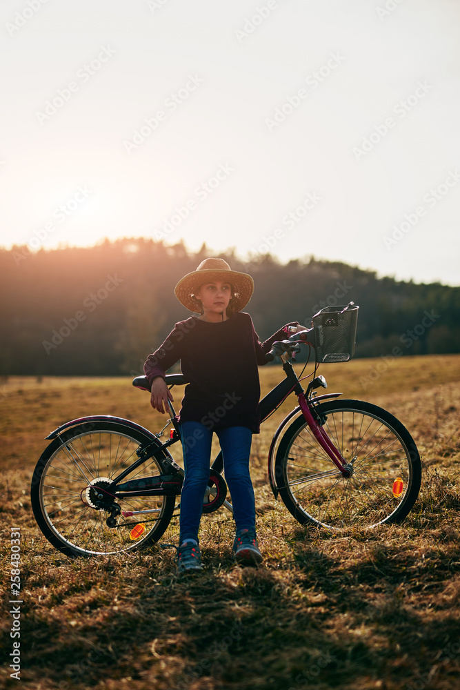Obraz premium Cute little ten year old girl riding bicycle on countryside.