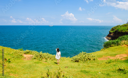 Chinese girl stands on grassland looking at ocean