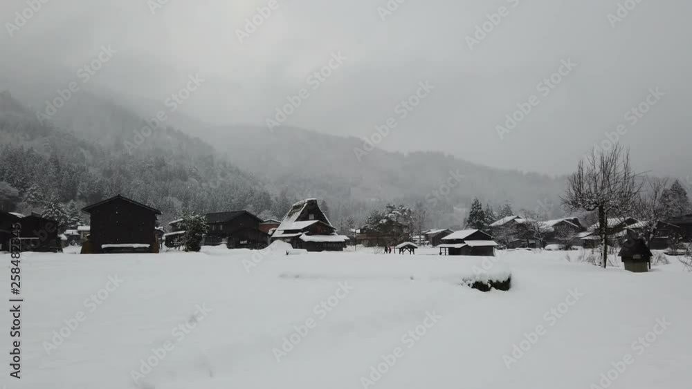 Snow falling in small town that has been covered by snow.