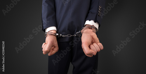 Close now arrested men hand with dark background and handcuffs 
