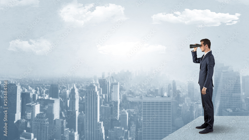 Fototapeta premium Businessman looking forward to a city with binoculars from skyscraper concept 