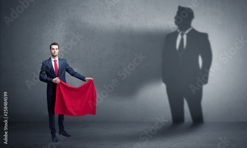 Businessman standing with red cloth on his hand and his shadow on the background 