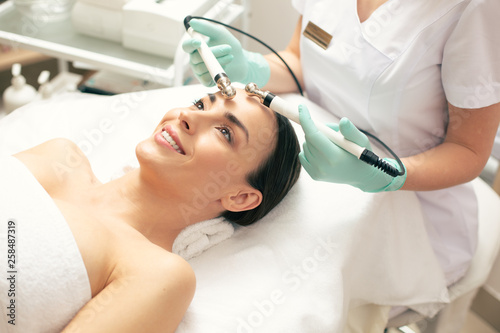 Happy woman enjoying microcurrent therapy and smiling