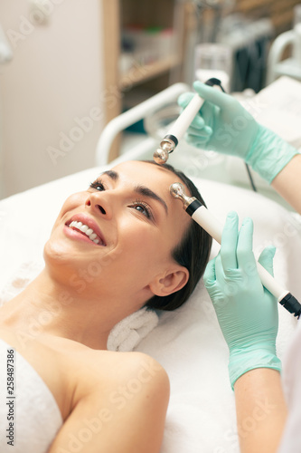 Face of happy woman enjoying facial procedure