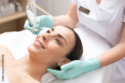 Smiling woman having her skin cleaned with modern tool