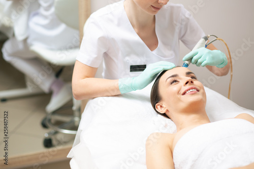 Careful cosmetologist nourishing the skin of her client