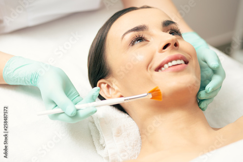Face of excited woman during the procedure of face peeling