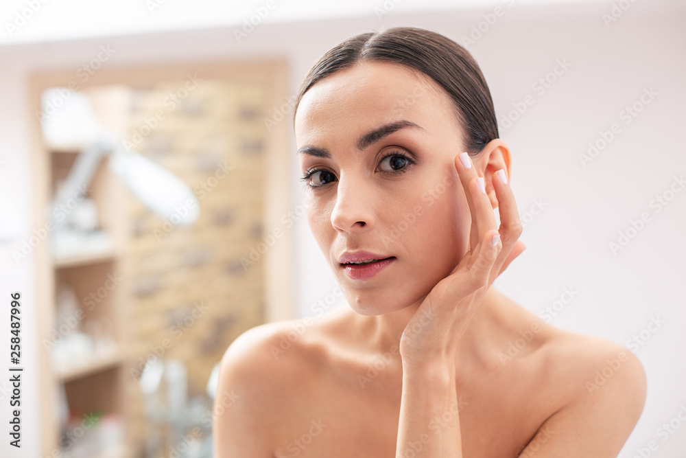 Calm lady with bare shoulders touching her face Calm lady with bare shoulders touching her face