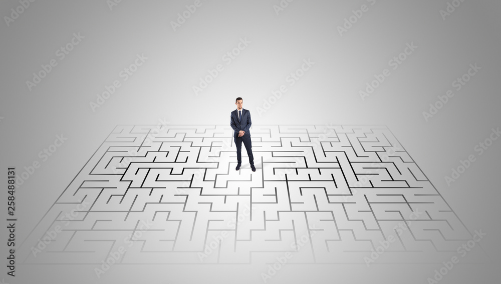 Elegant businessman looking for a solution in a middle of a maze
Elegant businessman looking for a solution in a middle of a maze
