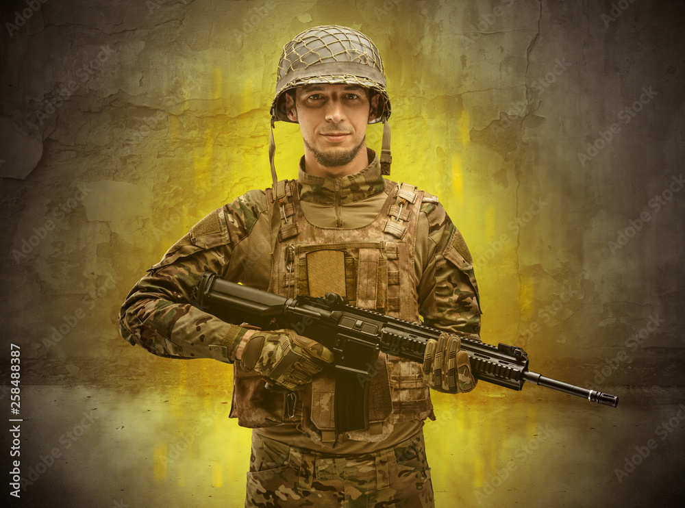 Fototapeta premium Hazard, menace soldier in a ruined crumbly building with arms on his hand 