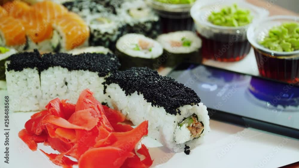 Woman waitress ran finger across screen and turned down phone call while spread sushi rolls on trays in cafe Woman waitress ran finger across screen and turned down phone call while spread sushi rolls on trays in cafe