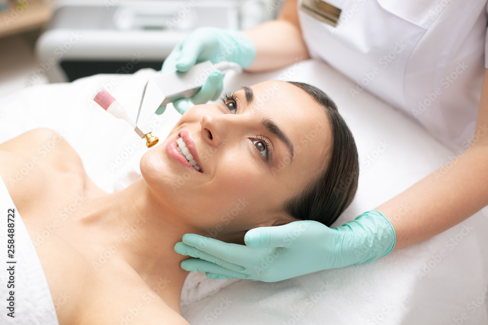 Hand of dermatologist touching the face of smiling woman Hand of dermatologist touching the face of smiling woman