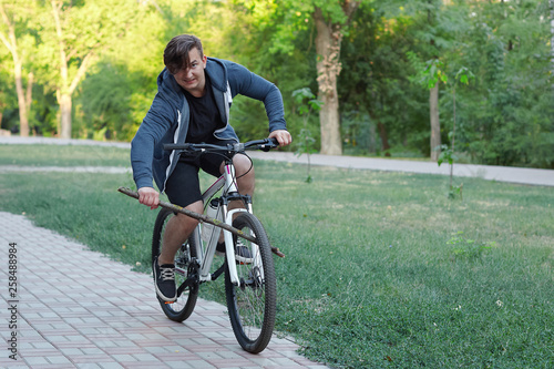 Valokuva Young caucasian man bicycling in the green park put the spoke in a wheel