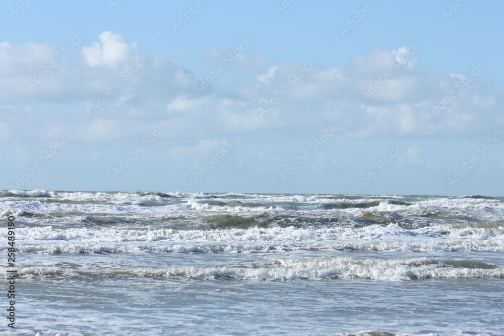 Waves in the sea and cloudy blue sky.