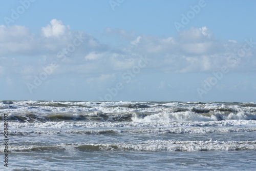 Waves in the sea and cloudy blue sky.