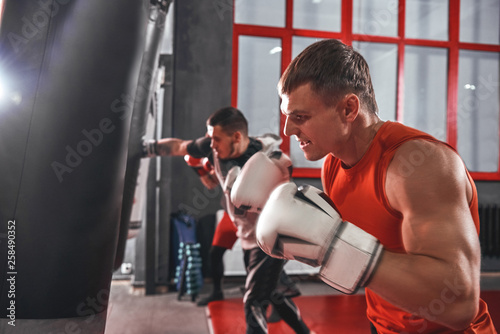 Never give up. Young muscular athletes in sports clothing boxing while exercising in boxing gym photo