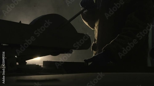 Disc grinder cutting a rectangular metallic tube with speedy yellow sparkles