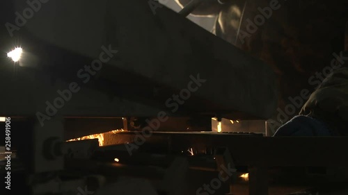 Grave flat metallic plate put on a machine tool in a dark workshop with spakles