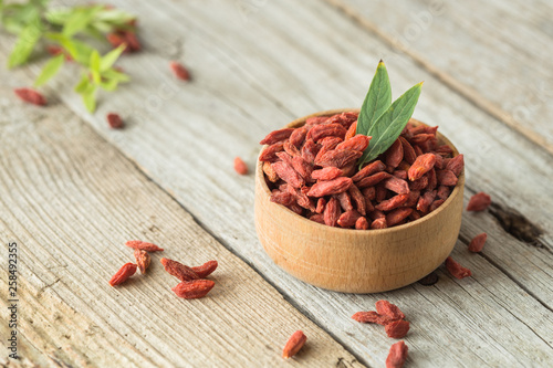 Goji in bowl on wood table. Top view of fresh goji in scoop and bowl. photo