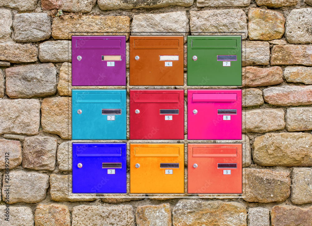 Boîtes aux lettres couleurs incrustées dans mur de pierres 