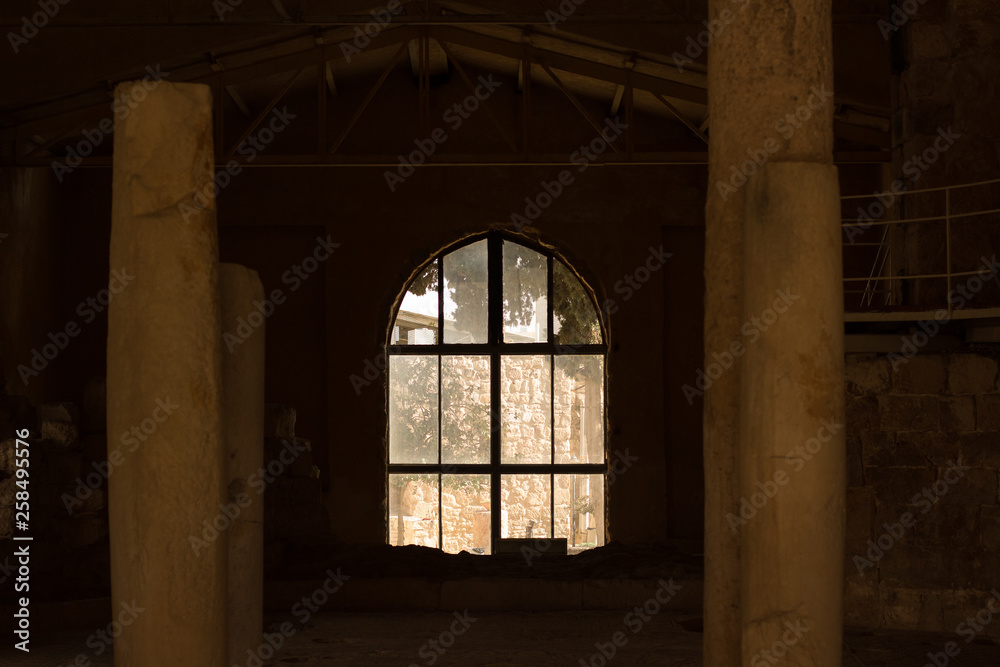 abandoned partly destroyed stone poor building interior inside environment symmetry foreshortening with columns and arch shape window in the center