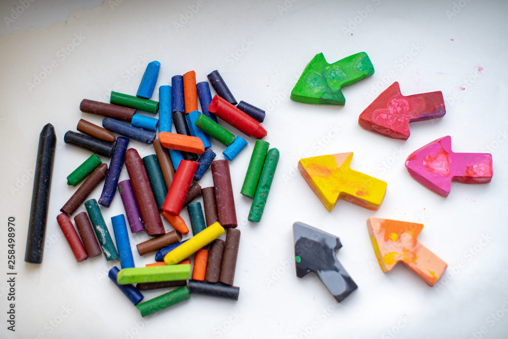 made homemade wax pencils from the wreckage of old crayons by melting them in the oven at high temperature in silicone form. crayons in the form of arrows lie on paper, hand child made homemade wax pencils from the wreckage of old crayons by melting them in the oven at high temperature in silicone form. crayons in the form of arrows lie on paper, hand child
