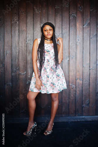 Сheerful african american young woman in summer dress and choker necklace against black wooden background.