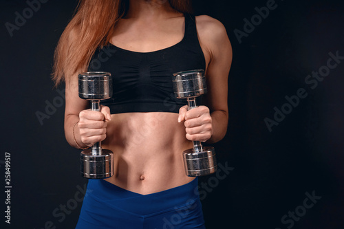 girl athletic lifts dumbbell. exercise for biceps with dumbbells. with free text space.