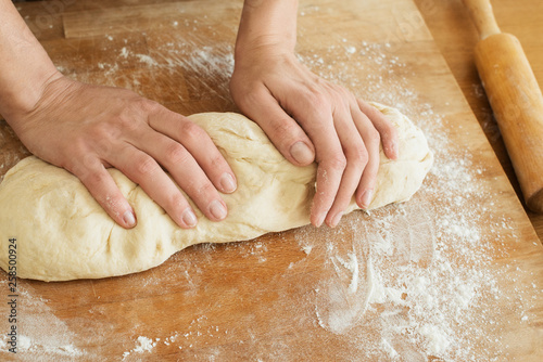 female hands knead the dough on a wooden board cooking baking.