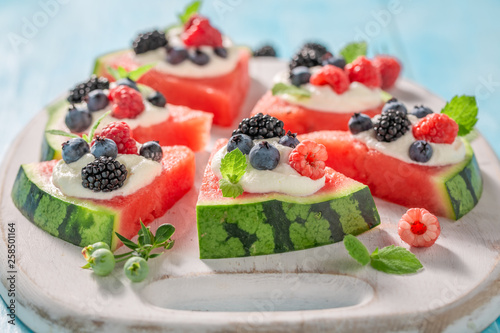 Sweet watermelon pizza with berries, whipped cream and mint leaves