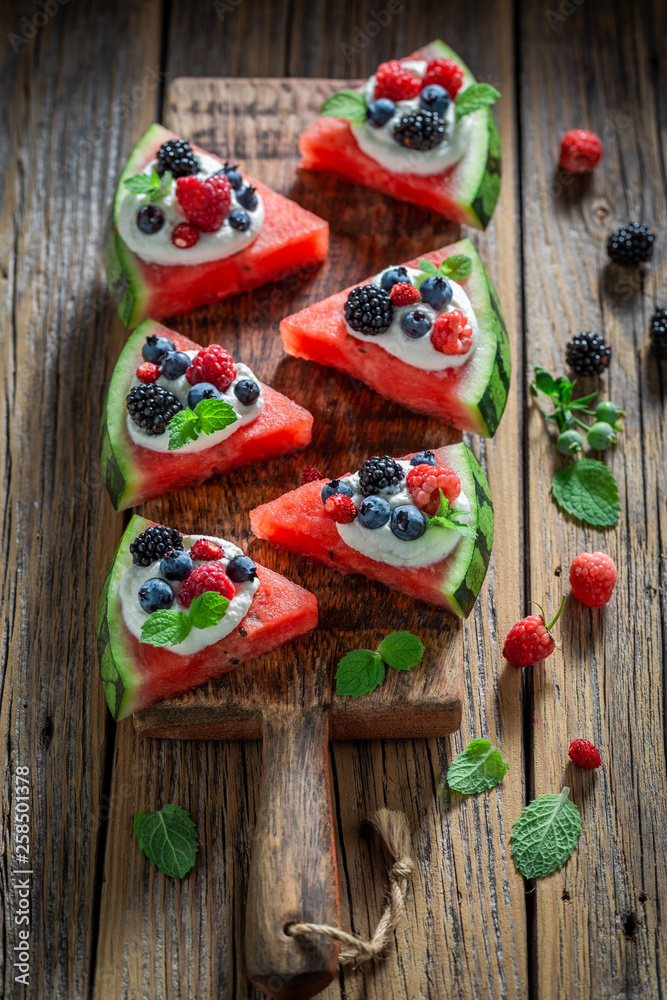 Tasty watermelon pizza with berries, whipped cream and mint leaves Tasty watermelon pizza with berries, whipped cream and mint leaves