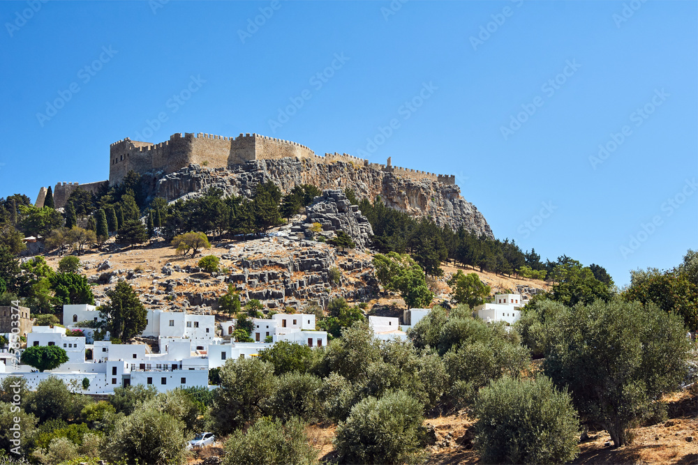 White houses of a greek town and a medieval fortress in Lindos .