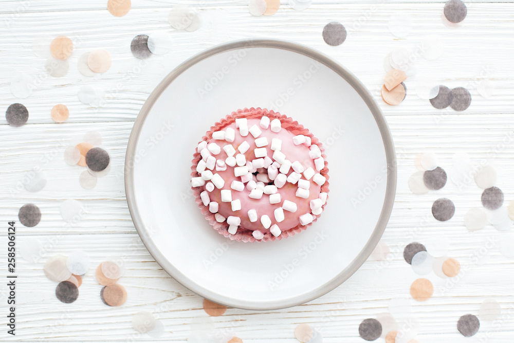 Delicious colorful donut with sprinkles and marshmallows on stylish plate on white table with confetti, flat lay. Party concept. No diet. Candy bar at wedding reception. Pink donut Delicious colorful donut with sprinkles and marshmallows on stylish plate on white table with confetti, flat lay. Party concept. No diet. Candy bar at wedding reception. Pink donut