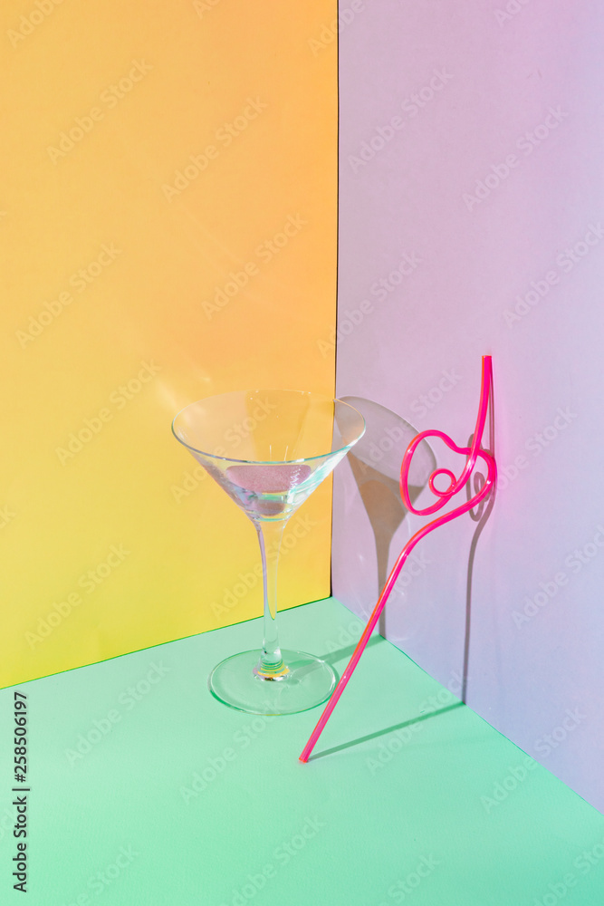 Cocktail glass with pink liquid and funny drinking straw. Strong fashion shadows. Concept of luxury relax with beverage on the beach. Cocktail glass with pink liquid and funny drinking straw. Strong fashion shadows. Concept of luxury relax with beverage on the beach.