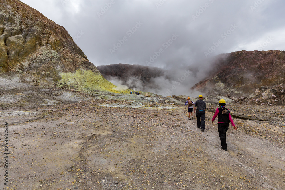 Tourists hiking towards the active vents in the crater of White Island Volcano, New Zealand.