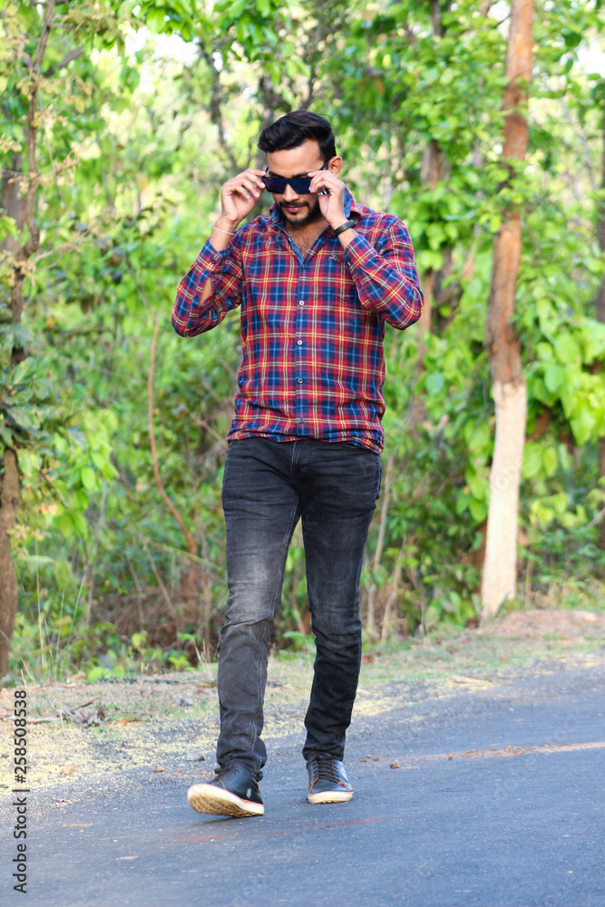 young man model walking in road holding his sun glass young man model walking in road holding his sun glass