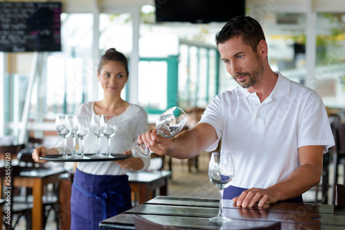 waitress and waiter cleaning glasses in a restaurant