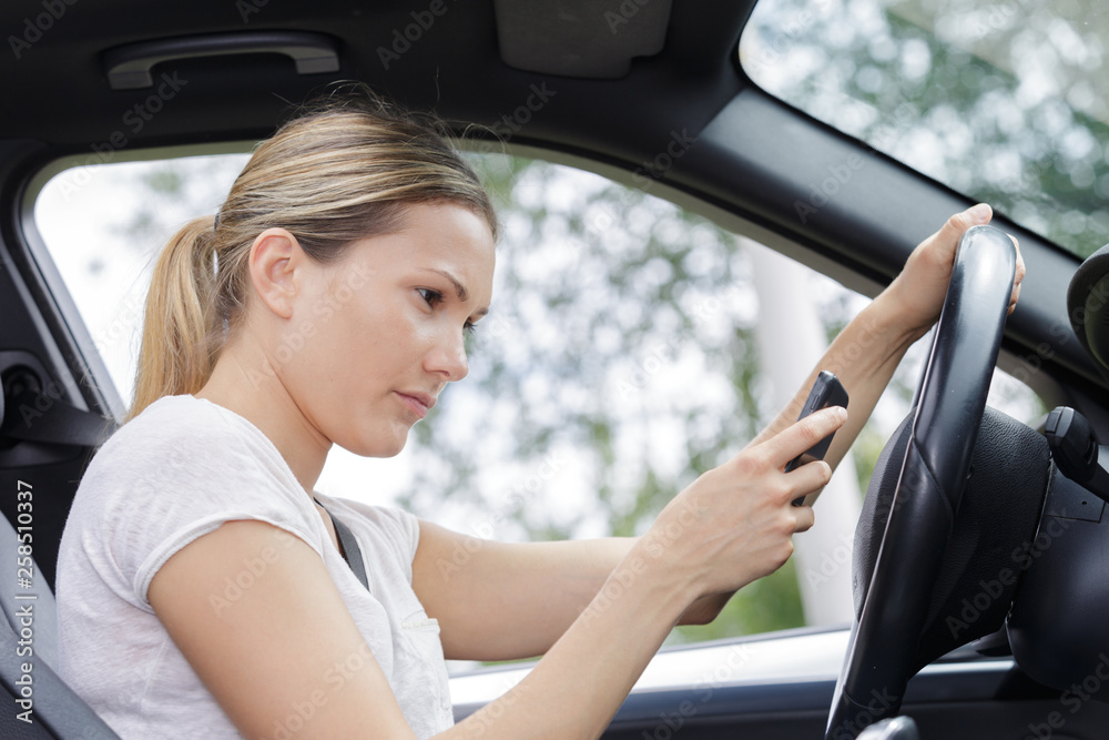 woman driving car and texting message on smartphone woman driving car and texting message on smartphone