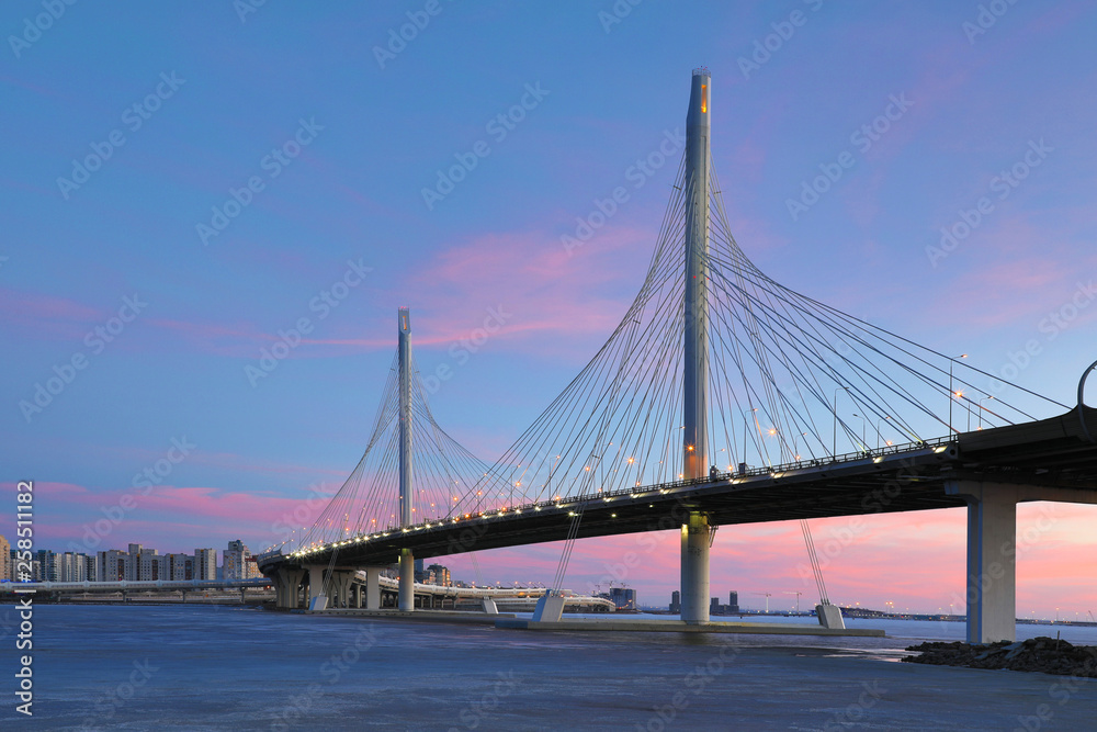 The bridge of circle highway road over Neva river near the mouth of it in the blue hour after the sunset. Night view on the buildings of Petersburg city and the Finish gulf