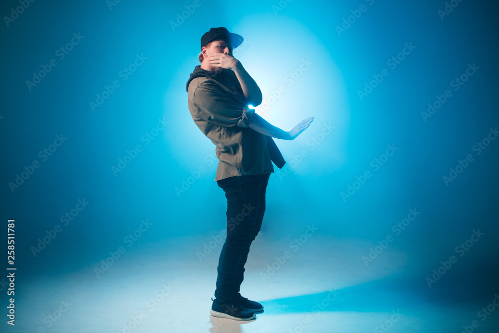 A dark silhouette of a singer on the stage, dancing alone during performance on dark blue neon background with smoke and lights. A dark silhouette of a singer on the stage, dancing alone during performance on dark blue neon background with smoke and lights.