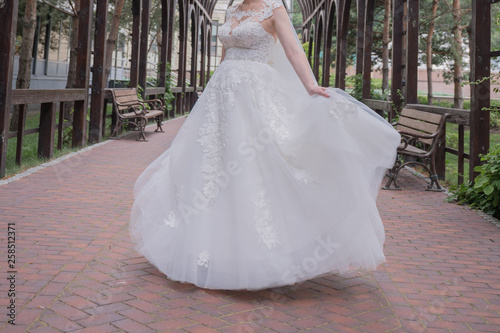 bride in wedding dress whirls in the park