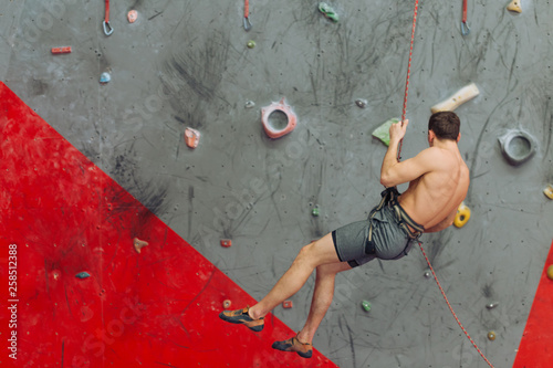 awesome strong guy going bouldering indoors. sporty brutal guy descending after climbing