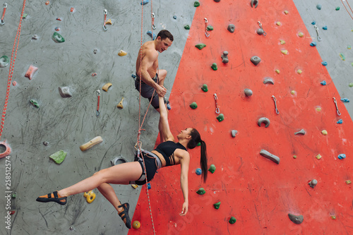 good looking man and woman having fun while climbing. positive acyive couple performing a stunt at gym. full length photo. copy space