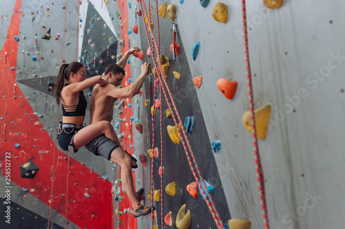 Sporty male and female taking part in a climbing competition. full length side view photo. copy space. students get pleasure from climbing