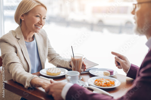 smiling gorgeous blonde woman listening to her boyfriend while sitting in the cafe . close up photo