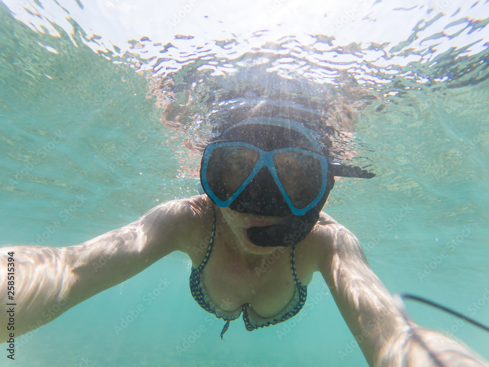 Fototapeta premium woman taking an underwater selfie while snorkeling in crystal clear tropical water
