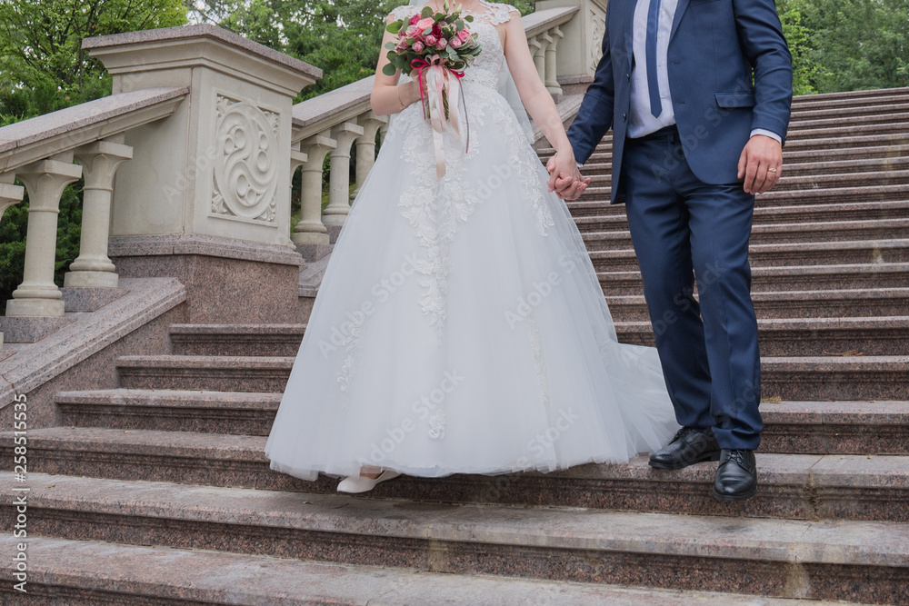 Fototapeta premium bride and groom walk together by the hand in the park