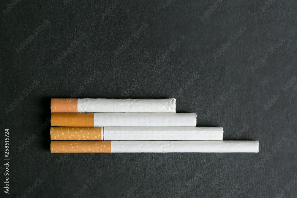 Cigarettes lie on a black background. Several cigarettes stacked neatly on a black background Cigarettes lie on a black background. Several cigarettes stacked neatly on a black background